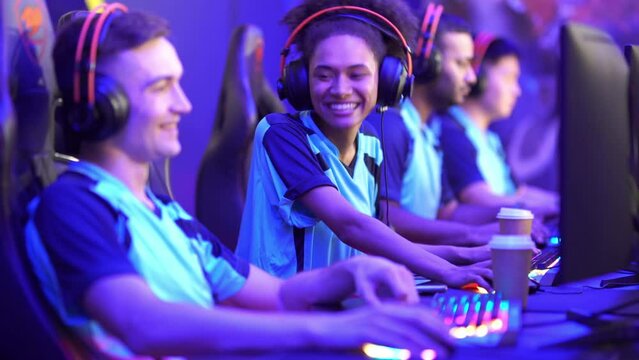 Multiracial cybersport gamers expressing success while raising hands up and smiling during participation in esports tournament in computer club