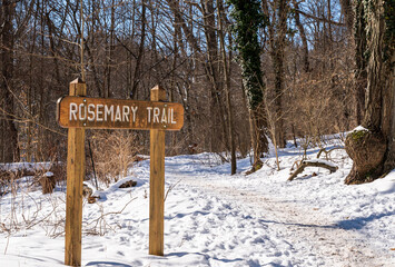 The wooden sign for Rosemary Trail in Frick Park, a city park in Pittsburgh, Pennsylvania, USA on a sunny winter day