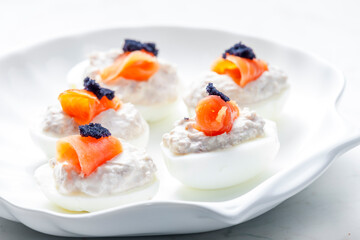 boiled eggs filled with tuna fish spread and smoked salmon and  black caviar on the top