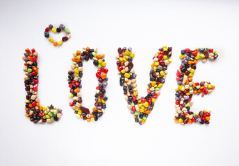 The word love is made from candies on a white background. Multi-colored sweets sea stones