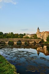 the church of Sanxay and the medieval arched stone bridge are reflected in the water surface of the river Vonne