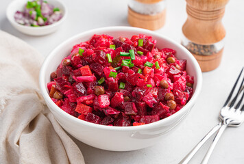 Traditional Russian salad vinaigrette with beets, potatoes, carrots and sauerkraut on a gray one.