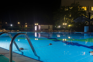 Swimming pool at night, illuminated turquoise water