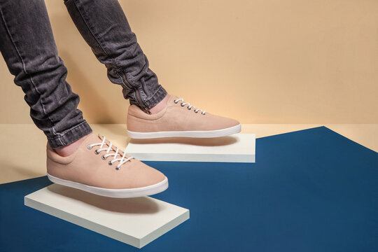 Man in beige color stylish sneakers with blue background