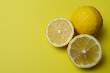 two half lemons and one whole lemon on a light yellow paper background with plenty of room for text