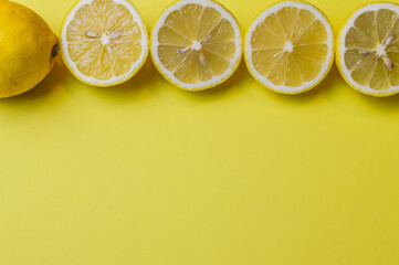 arrangement of four half lemons lined up with one whole lemon on a light yellow paper background and plenty of room to add text