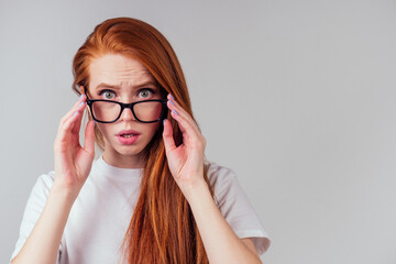 redhaired ginger woman wearing glasses and white cotton eco t-shirt in gray studio background