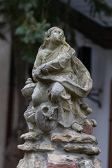Obraz premium Ancient sculpture of a Catholic saint with a skull underfoot in the yard of Church of the Blessed Virgin Mary, Mother of Consolation in Wroclaw