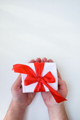 Moscow, Russia, January 2022, male hands on a white background hold a gift tied with a red ribbon