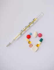 Moscow, Russia, January 2022, a thermometer and multi-colored pills on a white background
