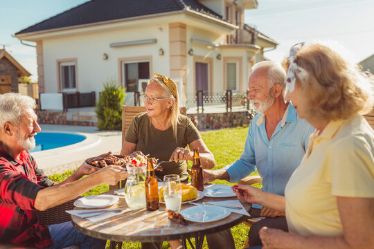 Party host serving food on a tray while having an outdoor lunch with friends - Powered by Adobe