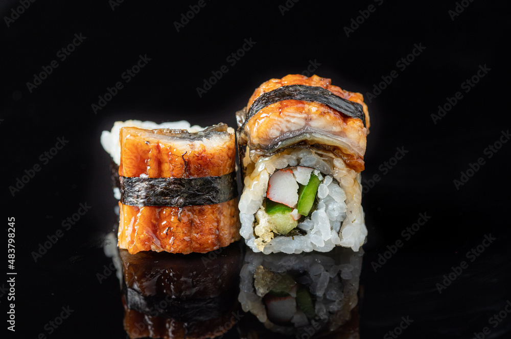 Sticker two eel fish sushis with crab stick and tempura on a black reflective surface