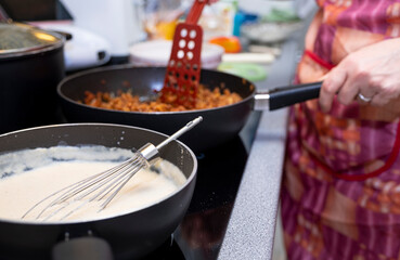 Caucasian young woman preparing food for the family, Italian dish, cannelloni with minced meat. Human hands close-up.