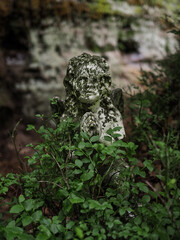 Little praying angel in sandstone rocks in the dark woods