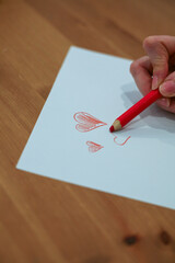 Woman drawing red hearts with a crayon