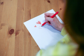 Woman drawing red hearts with a crayon