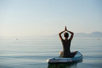  Mindful young woman sitting in lotus position with her palms joined above her head © Gajus
