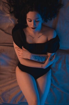 Sexy portrait of a woman lying in bed. Focus on the legs. Warm ambient light.