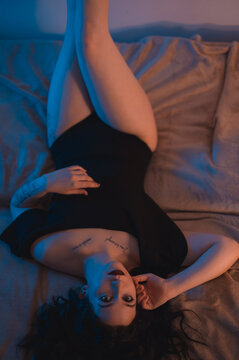 Sexy portrait of a woman lying in bed. Focus on the legs. Warm ambient light.