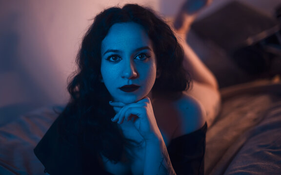 Sexy portrait of a woman lying in bed. Focus on the legs. Warm ambient light.