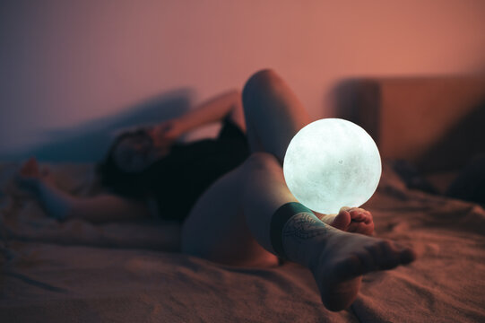 Sexy portrait of a woman lying in bed. Focus on the legs. Warm ambient light.