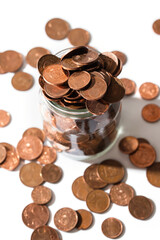 Shiny copper euro coins spilled from a glass jar.