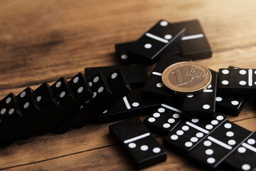 Shiny one euro coin lying on top of spilled domino tiles.