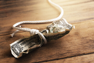 White rope tangled around a crumpled one dollar bill.