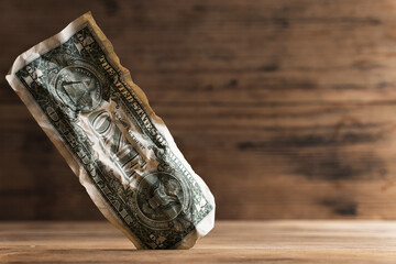 Closeup shot of a crumpled one dollar bill stuck in a gap in the floor.