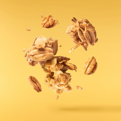 Fresh Granola flakes falling in the air on yellow background.