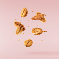 Fresh Granola flakes falling in the air on yellow background.