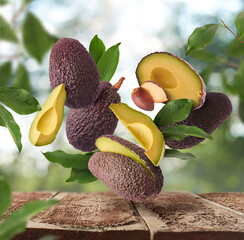 Fresh raw avocados falling in the air on wooden table
