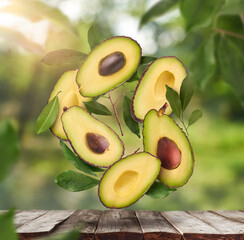 Fresh raw avocados falling in the air on wooden table