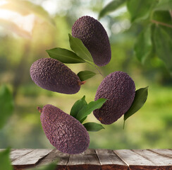 Fresh raw avocados falling in the air on wooden table
