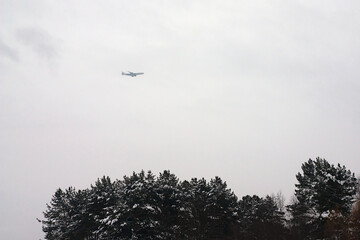 an plane in the cloudy sky over a forest park