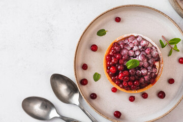 Fresh berry tart with cowberry, powdered sugar and mint in a plate on white background. Tasty dessert. Top view