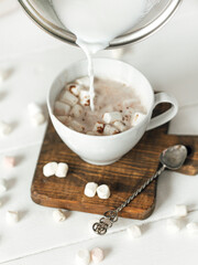 close up of a cup of coffee with whipped cream and a glass of milk on a white wooden background