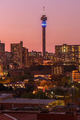 A vertical cityscape taken after sunset with a pink sky,, of the central business district of the city of Johannesburg, South Africa