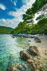 Fototapeta Wybrzeże i morze Chorwacji z kamienną plażą i niebieskim niebem z białymi chmurami obraz