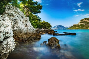 Wybrzeże i morze Chorwacji z kamienną plażą i niebieskim niebem z białymi chmurami - obrazy, fototapety, plakaty