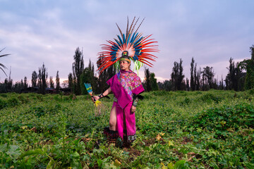 Aztec dancer in the field also known as "Chinampa" in Xochimilco, Mexico, with the traditional Aztec clothing and accessories like "Penachos" or "Huipiles".