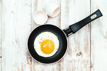 Fried egg in a frying pan on a wooden background.