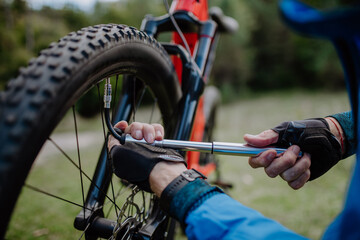 Close-up of a man pumping bicycle wheel in nature.