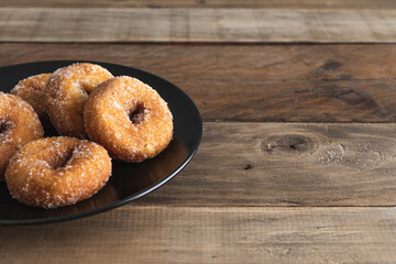 Sweet carnival dessert donuts on black plate on wooden background. Copy space.