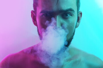 Handsome young man with wet skin in ultraviolet light smoking vape