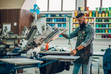 Male worker using printing machine in a workshop