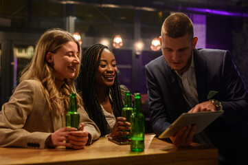 Cheerful colleagues drinking beer in the bar together after work