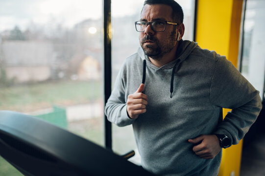 Middle aged man running on a treadmill in the gym
