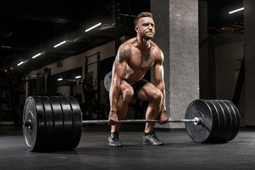 Obraz na płótnie Canvas Muscular man working out in gym doing deadlift exercise, strong male naked torso abs