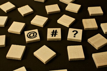 Fototapeta premium Scattered wooden squares. in the middle, the symbol of a question mark and a hashtag with a monkey. symbol of, for example, a technology question, an ambiguity about IT or Internet issues. 